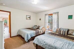 A bedroom with two beds, a window with curtains, and a door leading to a balcony. - Enjoy some mountain time with your favorite canine at Alpine View! (Dry Fork)