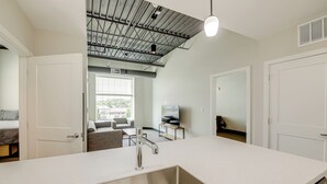 Eine moderne Küche mit einer großen Kochinsel, einer Spüle aus Edelstahl und einer Decke mit freiliegenden Leitungen.