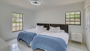 A bedroom with two beds, a nightstand, a window, and a ceiling light. - Luxe Wimauma Home w/ Pool & Lake Views! (Wimauma)