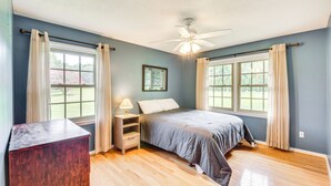 A bedroom with a bed, nightstand, lamp, and a ceiling fan. - West Union Home w/ Saltwater Pool on 2 Acres! (West Union)