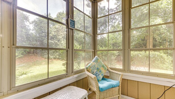 Una sala de estar con ventanales amplios, muebles de mimbre y vistas al exterior.