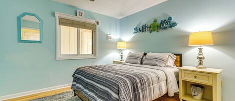 A bedroom with a bed, nightstands, a window, and a wall decoration.
