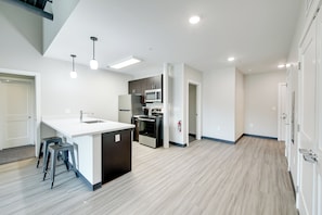 A modern kitchen with a central island, stainless steel appliances, and a light wood floor. - Bloomington Apartment, 3 Mi to IU Memorial Stadium (Bloomington)