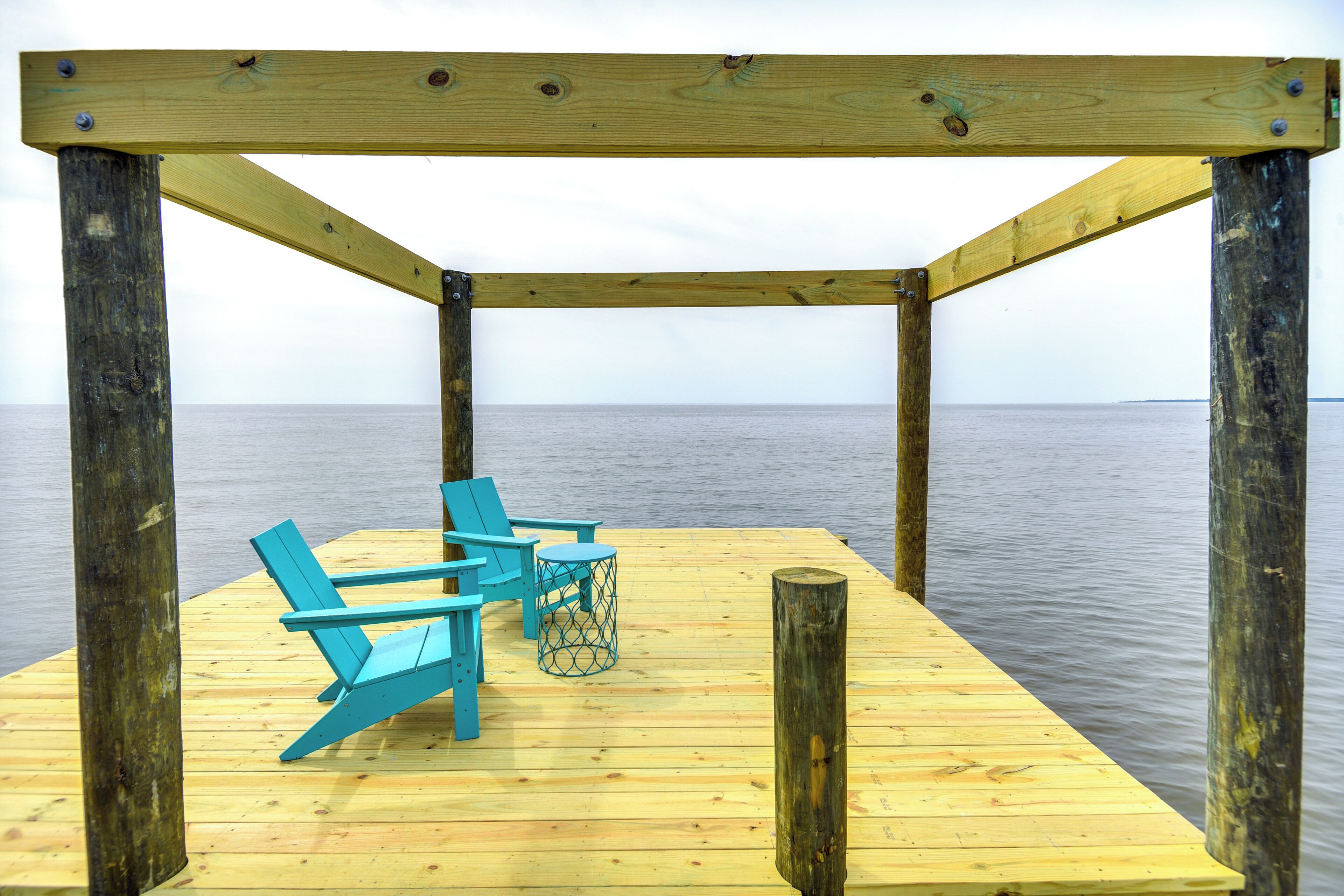 A wooden deck with a simple railing and two blue chairs.