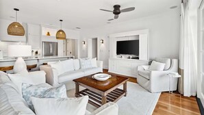 A modern living room with white furniture, a wooden coffee table, and a television. - Rooftop Comm Pool - WaterHouse 204 by Royal Destinations (Inlet Beach)