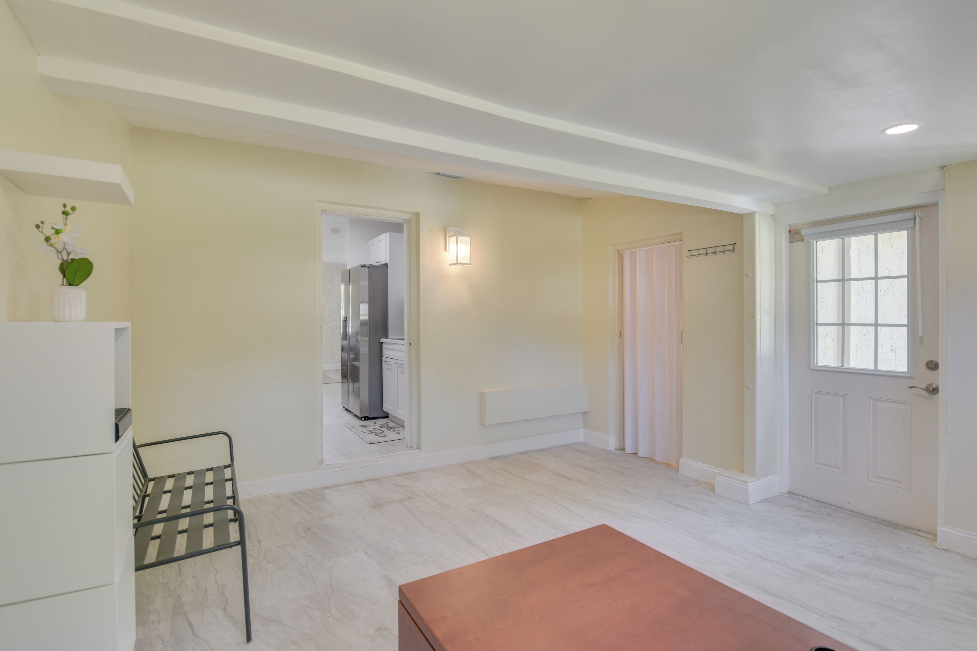 Une pièce spacieuse avec une porte blanche, une fenêtre et une chaise en métal.