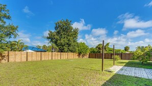 A grassy backyard with a wooden fence, a paved walkway, and a tree. - 5 Mi to Beach: Pet-friendly Port Charlotte Home (Port Charlotte)