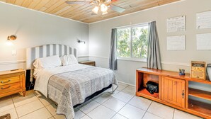A bedroom with a bed, wooden headboard, a ceiling fan, a window with curtains, a nightstand, a dresser, and a wall with notes. - 5 Mi to Beach: Pet-friendly Port Charlotte Home (Port Charlotte)