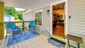 A covered porch with two chairs, a small table, and a welcome mat.