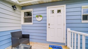 A porch with a white door, a wicker chair, a glass table, and a welcome mat. - Charming Geneva Vacation Rental ~ 5 Mi to Lake! (Geneva)