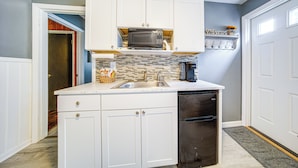 A compact kitchen with white cabinets, a microwave, a refrigerator, and a sink. - Charming Geneva Vacation Rental ~ 5 Mi to Lake! (Geneva)