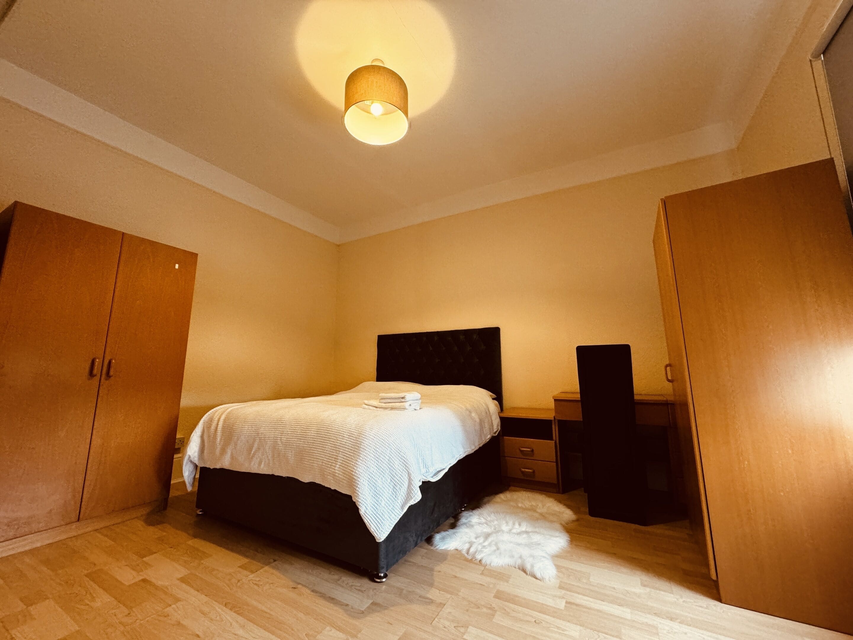 Una camera da letto con un letto, un'armadietto in legno e un piccolo comodino.