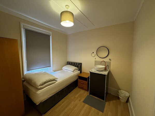 Un dormitorio con cama, mesita de noche, espejo, ventana y puerta.