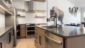 Eine moderne Küche mit Edelstahlgeräten, einer großen Kochinsel und einem Wandbild von Bison.