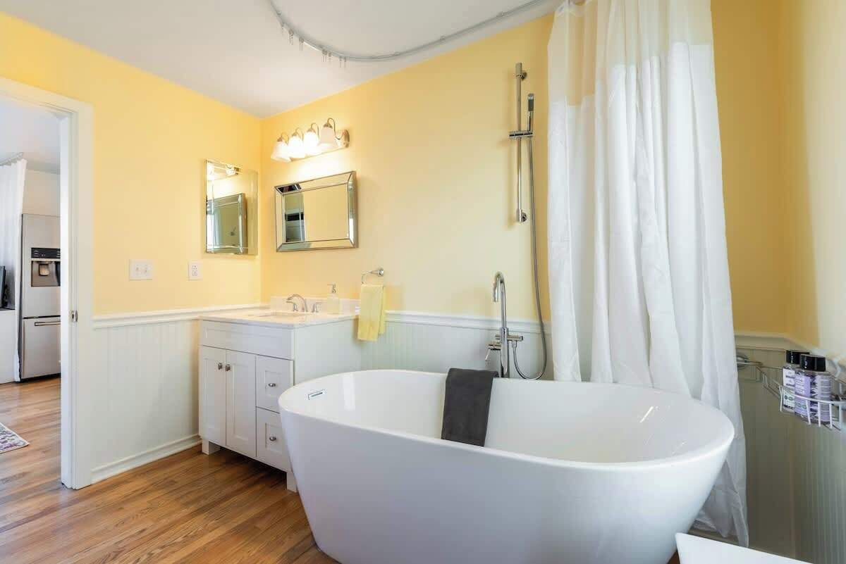 Ein Badezimmer mit freistehender Badewanne, einem Waschbecken mit Spiegel darüber und einer Duschkabine.