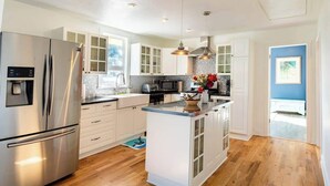 A modern kitchen with stainless steel appliances, white cabinetry, and a central island. - Orca Haven: 2BR w/ Scenic Views, Richmond Beach (Shoreline)