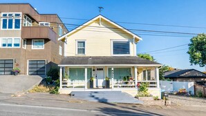 A two-story house with a front porch, garage, and a small garden area. - Orca Haven: 2BR w/ Scenic Views, Richmond Beach (Shoreline)