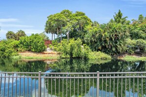 A serene lakeside view with a wooden bridge, lush greenery, and a clear sky. - F-139 - First Floor Deluxe Condo, Sleeps 6 (Naples)