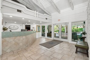 A reception area with a counter, a sign reading 'Park Shore Resort,' and a view of the outdoors through glass doors. - B-110 - Completely renovated first floor condo (Naples)
