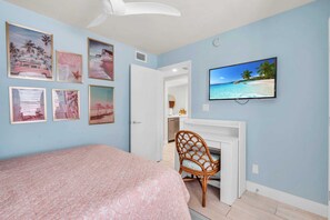 A bedroom with a bed, a TV mounted on the wall, and several framed pictures. - B-110 - Completely renovated first floor condo (Naples)