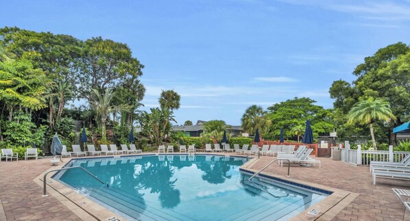 Une piscine avec des chaises longues et une terrasse en briques.