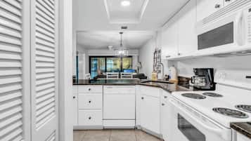 A modern kitchen with white cabinetry, a built-in oven, and a microwave.