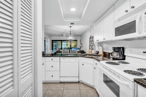 A modern kitchen with white cabinetry, a built-in oven, and a microwave.