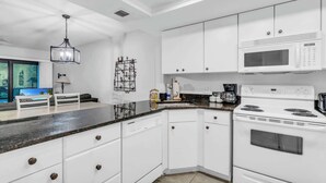 Una cucina moderna con mobili bianchi, un forno a microonde, un fornello e una macchina da caffè.