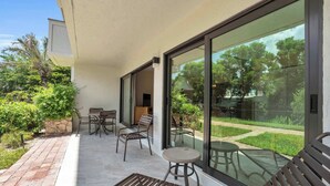 Un patio exterior moderno con una zona de estar, una jardinera de piedra y vistas a un jardín y árboles.