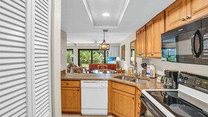 Una cocina moderna con armarios de madera, lavavajillas, estufa grande y microondas.
