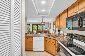 A modern kitchen with wooden cabinets, a dishwasher, a large stove, and a microwave. - I-151 - First Floor With Resort View & Sleeps 4 (Naples)