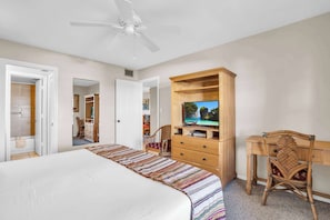 A bedroom with a bed, a television on a wooden cabinet, a ceiling fan, and a door leading to another room. - I-450 - Exceptional Lake View 4th Floor Condo! (Naples)