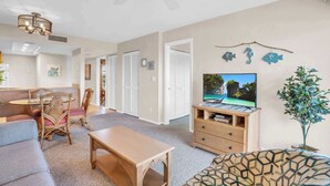 A spacious living room with a television, a dining area, and a cozy seating area.