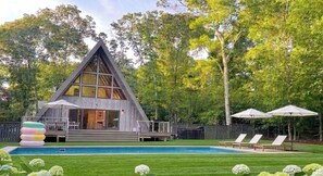 A modern A-frame cabin with a pool, deck chairs, and umbrellas. - Luxury | 5* Rating | Heated Pool | 10m to US Open (Hampton Bays)