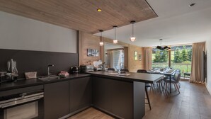 Una cocina moderna con una isla central, electrodomésticos de acero inoxidable e iluminación colgante.