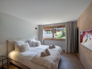 A bedroom with a large bed, a TV on the wall, and a window with curtains. - Modern 133m² apartment in Courchevel, close to cable car, with WiFi and parking (Courchevel 1550)