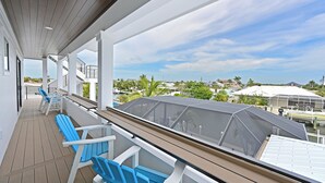 Ein überdachter Außenbereich mit blauen Stühlen und Blick auf die umliegende Nachbarschaft.