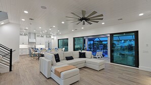 Ein modernes Wohnzimmer mit einer Eckcouch, einem Essbereich mit Tisch und Stühlen sowie einer Küche im Hintergrund.
