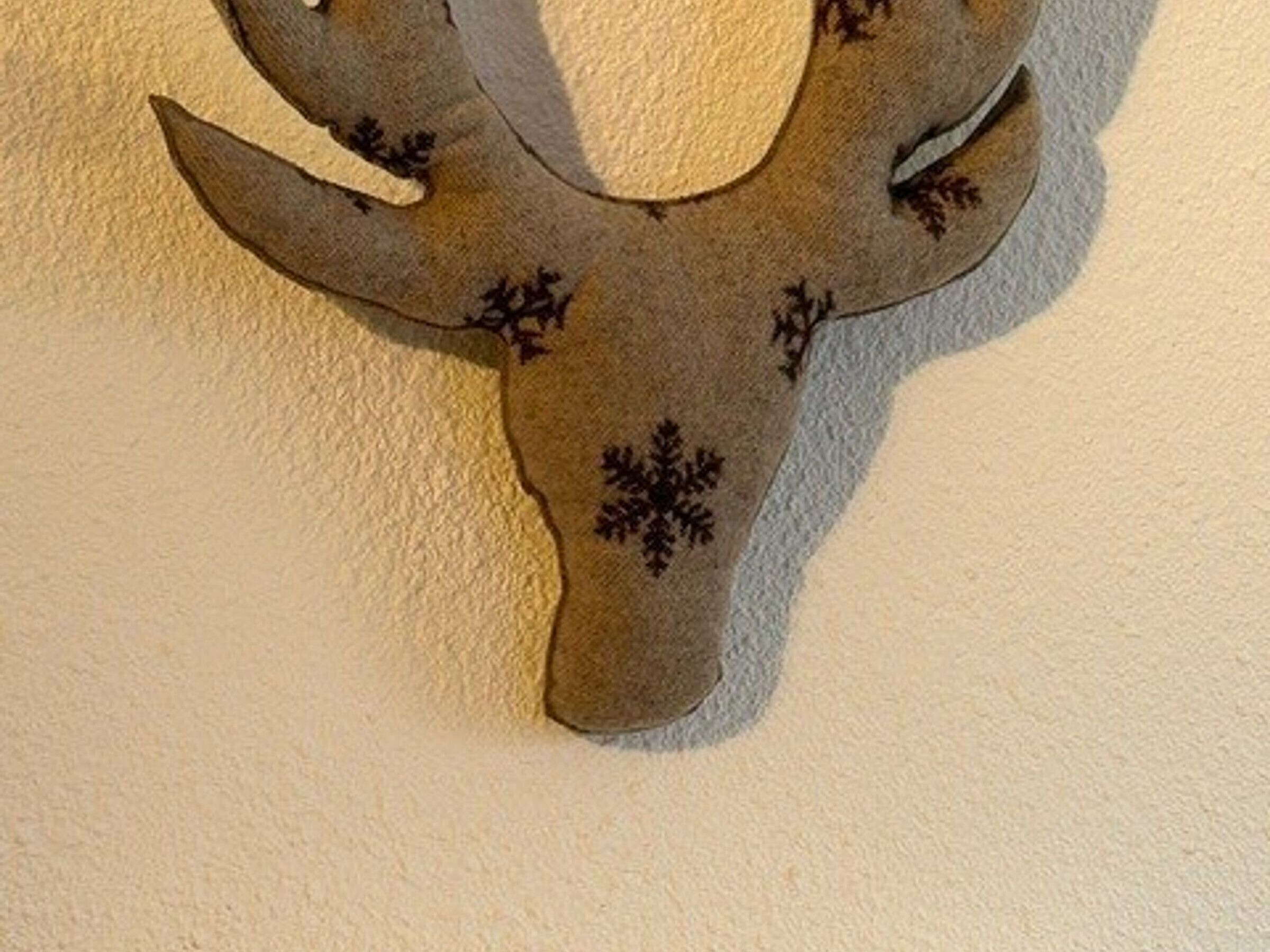 Une tête de cerf décorative, fixée au mur et ornée de motifs en forme de flocons de neige.