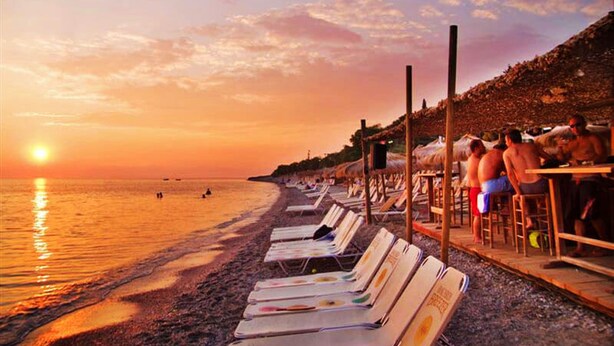 A beach with sun loungers and a sunset.