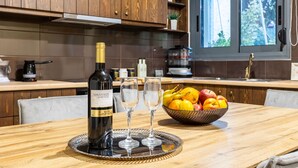 A kitchen with wooden cabinets, a dining table with a wine bottle, two glasses, and a fruit bowl.