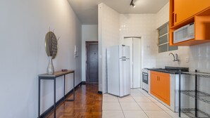 A modern kitchen with a refrigerator, microwave, and orange cabinets.
