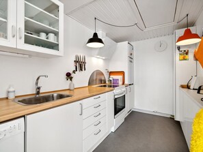Een koelkast, een oven, een vaatwasser, kookgerei, borden en bestek