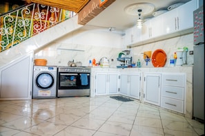 A kitchen with a washing machine, oven, and white cabinets.