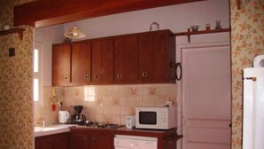 A kitchen with wooden cabinets, a microwave, a dishwasher, and a stove. - Maison D'été Plage a Pied Oleron (Saint-Pierre-d'Oléron)