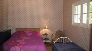 A bedroom with two beds, a nightstand, a lamp, a chair, and a window. - Maison D'été Plage a Pied Oleron (Saint-Pierre-d'Oléron)