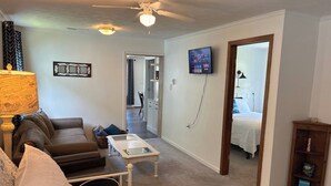 Una sala de estar con un sofá, una mesa de centro, un televisor y una estantería.