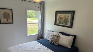 A bedroom with a bed, a window, and two framed pictures on the wall. - Relax and Unwind at the Cozy Cabin on Heaton Lake. (Elkhart)