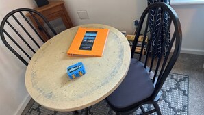 A round table with a book and a small blue object on it, surrounded by two black chairs. - Relax and Unwind at the Cozy Cabin on Heaton Lake. (Elkhart)