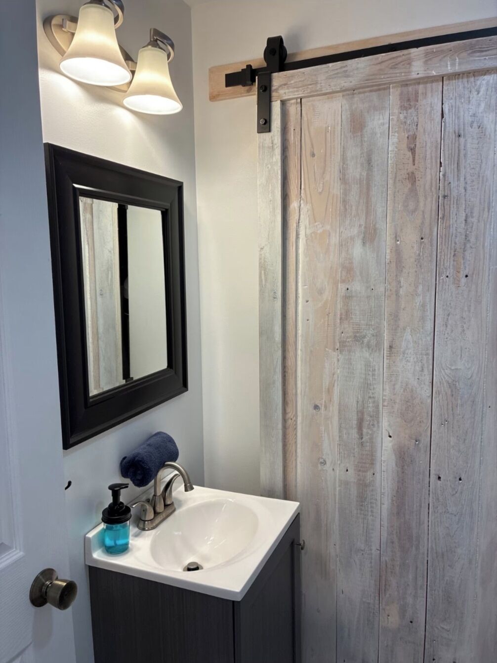A bathroom with a white sink, a mirror, and a wooden door.